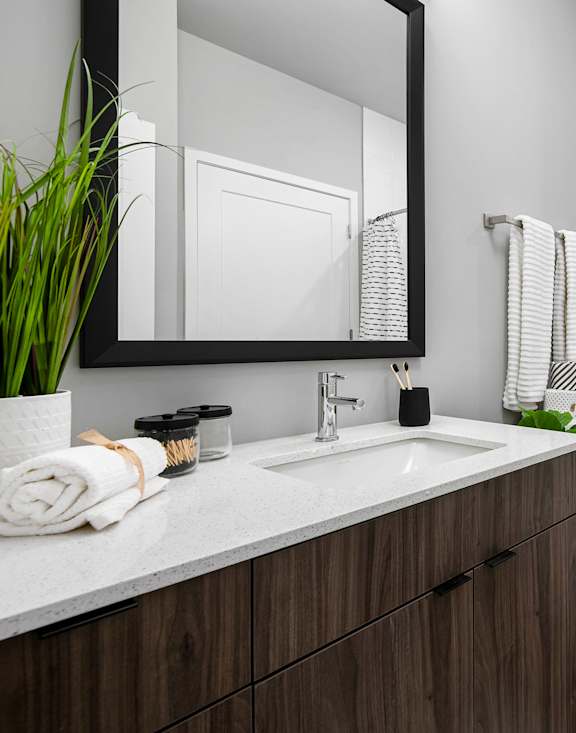 a bathroom with gray walls and a white countertop with a sink and mirror