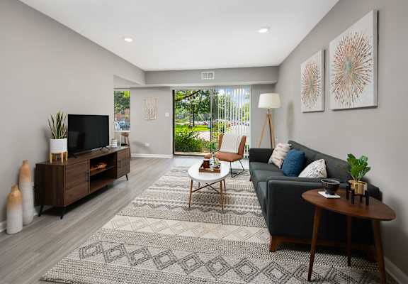 A living room with a grey couch, a wooden coffee table, and a television.