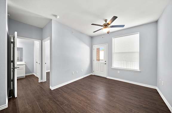 an empty living room with wood floors and a ceiling fan