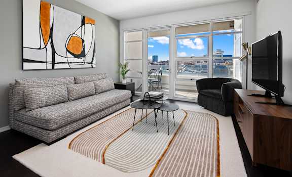 a living room with a couch and a tv and a balcony