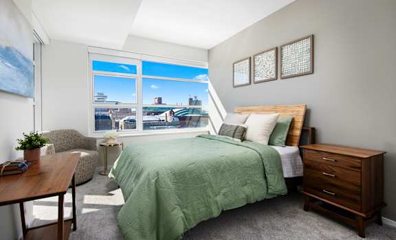 a bedroom with a large window and a green bed