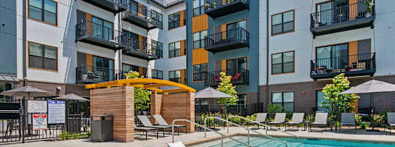 a swimming pool with lounge chairs in front of an apartment building
