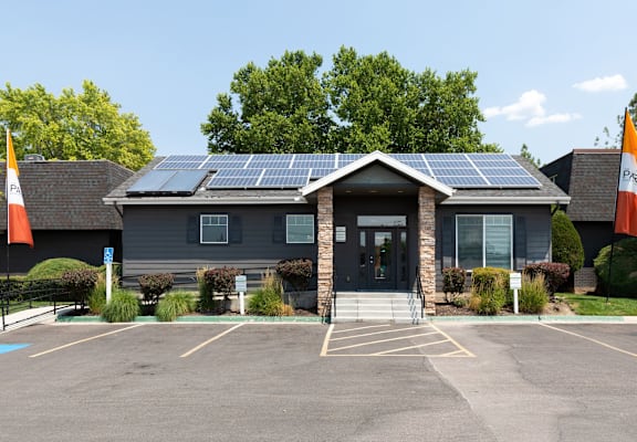 A building with solar panels on the roof and flags on the front.