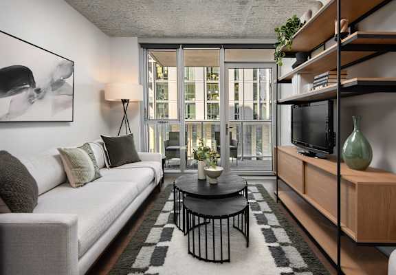 A living room with a white couch, a black coffee table, and a large window.