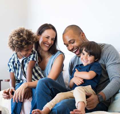 A family of four is sitting on a couch together.
