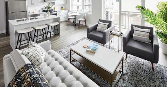 a living room with a kitchen and a couch and chairs