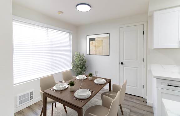 A dining room with a table set for two and a plant on the windowsill.