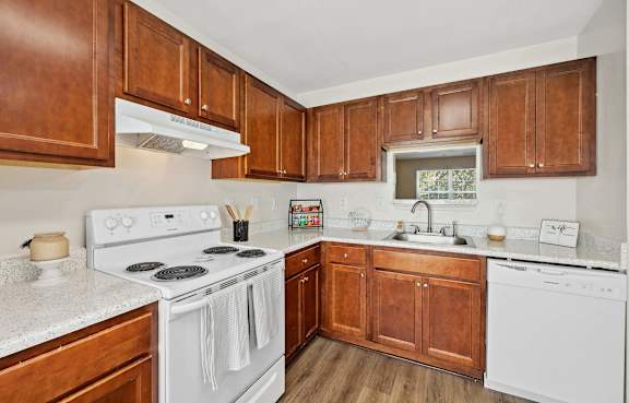 A kitchen with white appliances and wooden cabinets.