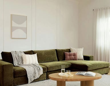 A living room with a green couch, a wooden coffee table, and a grey rug.