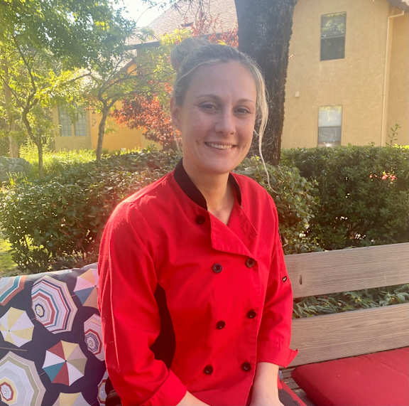Woman wearing red culinary jacket at Hilltop Commons Senior Living, Grass Valley, CA