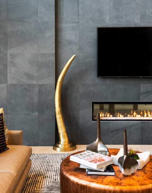 A living room with a fireplace, a couch, and a TV mounted on the wall.