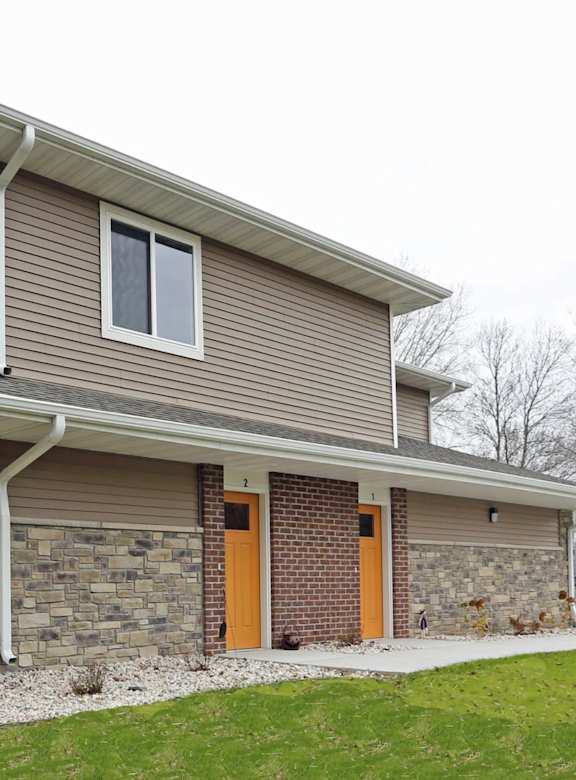 a house with brown siding and orange doors