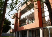Thumbnail 2 of 6 - a red brick building with balconies and a tree