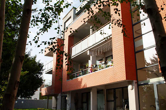 a red brick building with balconies and a tree