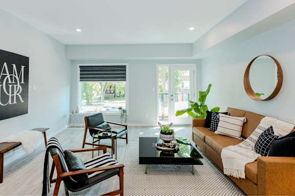 A living room with a brown couch, a coffee table, and a mirror.