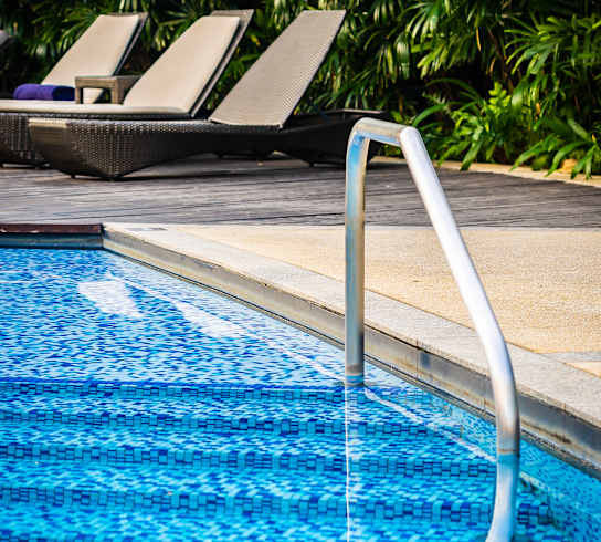 A pool with a slide and sun loungers.