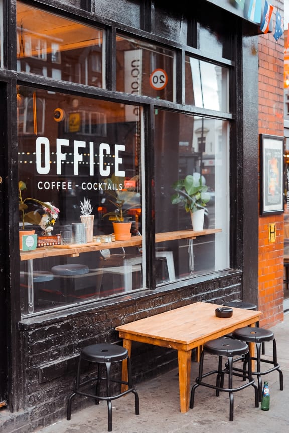 a wooden table in front of a coffee shop window
