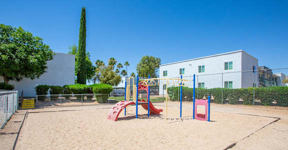 A playground with a red slide and a blue climbing frame.