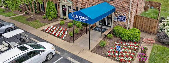 A car is parked in front of a building with a blue awning.