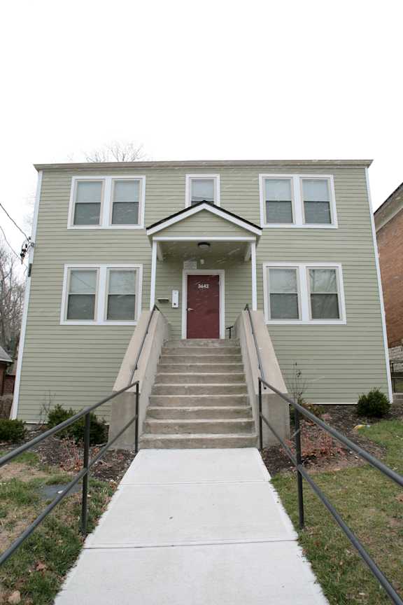 the front of an apartment building with stairs and a red door