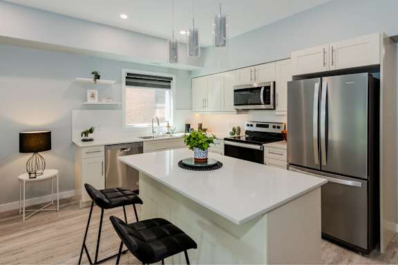 A modern kitchen with a white island and stainless steel appliances.
