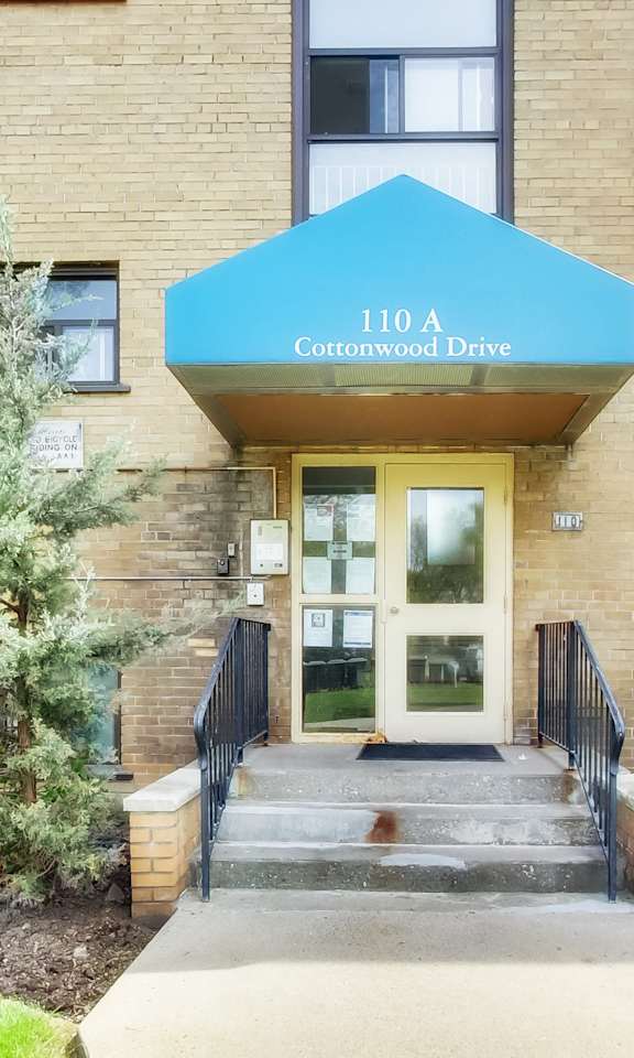 The front of a building with a blue awning that says Cottonwood Drive.
