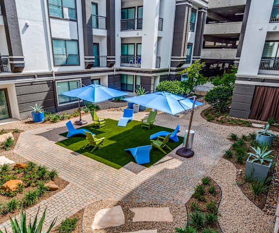 an outdoor area with umbrellas and chairs in an apartment building