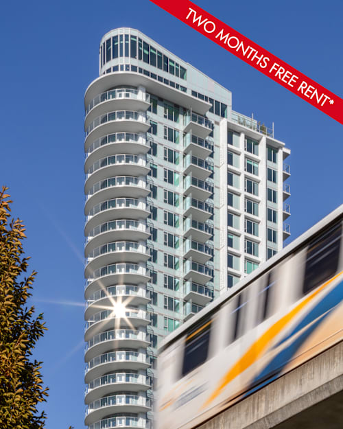 A modern building with a train passing by and a sign offering two months free rent.