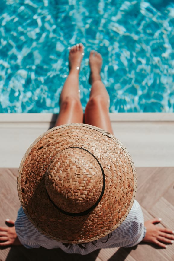A swimming pool surrounded by lounge chairs and umbrellas in front of apartment buildings.