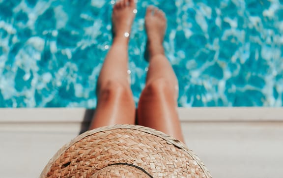 a woman with a straw hat laying by a pool