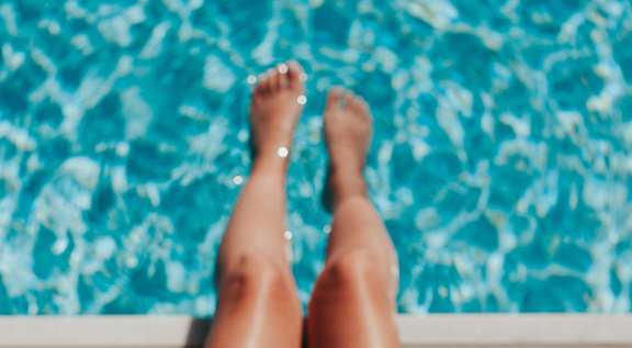 A person wearing a straw hat is sitting by a pool.