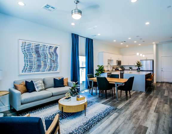 a living and dining room area with a couch table and chairs and a kitchen in the background