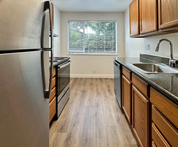 a kitchen with stainless steel appliances and wooden cabinets at The Chase Apartment Homes, Oakland, 94606