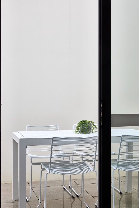 a white table with chairs and a plant in a room