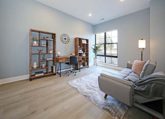 A living room with a grey couch and a wooden bookshelf.