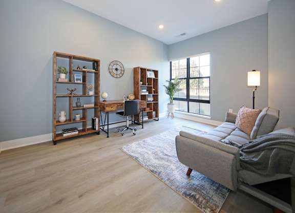 A living room with a grey couch and a wooden bookshelf.