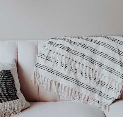 A white couch with a black and white pillow and a white and black striped throw.