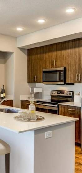A modern kitchen with a white countertop and wooden cabinets.