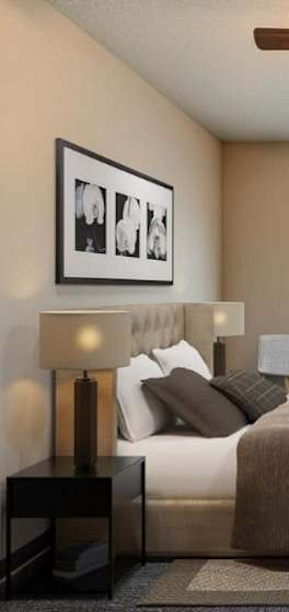 A bedroom with a bed, nightstand, and framed pictures on the wall.