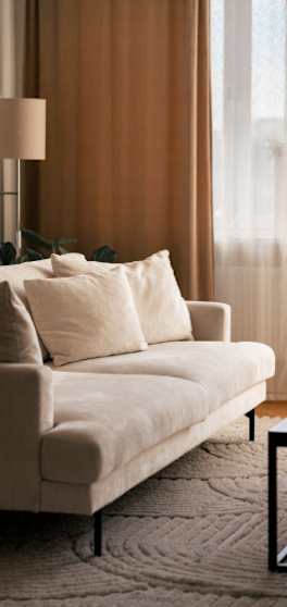 A beige sofa with a lamp beside it.