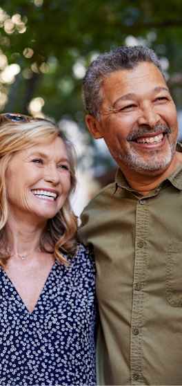 A man and a woman are standing close together, both smiling.