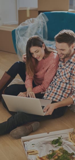 a man and woman sitting on the floor with a laptop