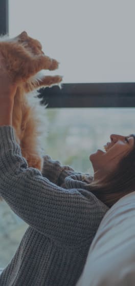 a woman sitting on a couch with her cat looking out the window