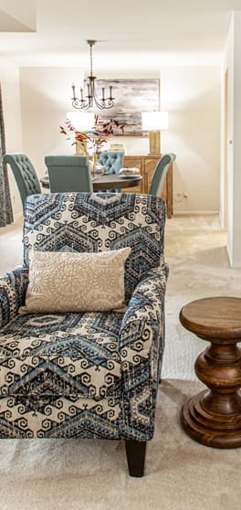 a living room with a blue and white chair and a table in the background