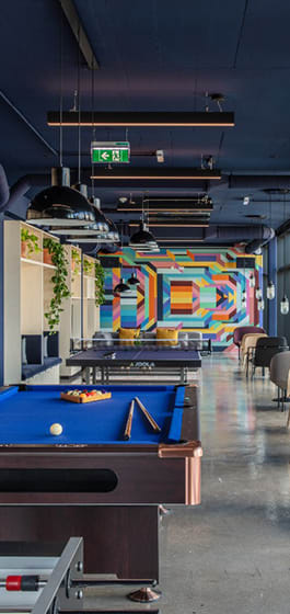 a pool table and a ping pong table in a room with a mural on the wall