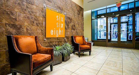 Two chairs are in front of a wall with a poster that says "Six Six Eight".