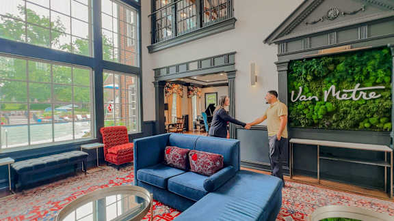 A man and woman are standing in a room with a large window and a sign at Lakes Edge Apartments, North Carolina, 27409