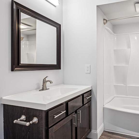 A white sink with a silver faucet and a brown mirror above it.