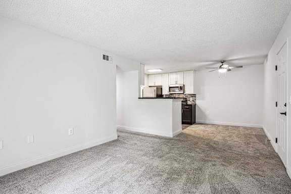 A spacious living room with a kitchenette in the background.