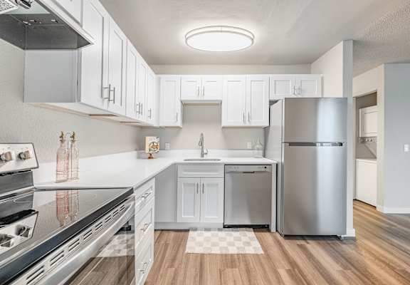A modern kitchen with white cabinets and stainless steel appliances.